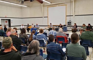 People sitting in chairs listen to a presentation