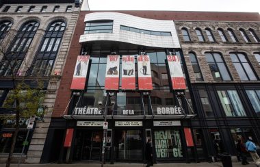 La façade du théâtre La Bordée, situé sur la rue Saint-Joseph Est. En haut des grosses lettres blanches qui nomment l'institution, des bannières rouges et blanches annoncent les spectacles en salle.