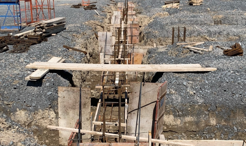Construction de la fondation de la nouvelle concession Laplante à l’extérieur, composée de bois et de métal dans un troue creusé entouré de roches.
