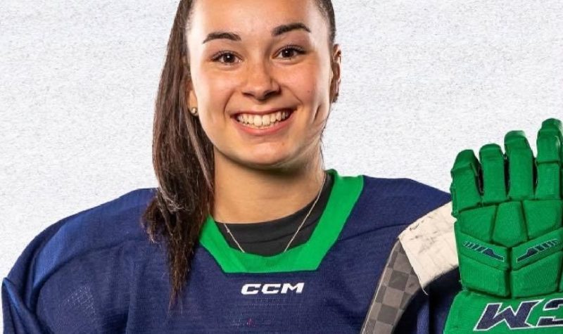 Une jeune fille habillée en équipement de hockey devant un fond blanc