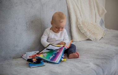 Un jeune enfant entouré de livre en tissus en regarde un.