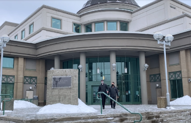 Two people leaving the Prince George courthouse during winter.