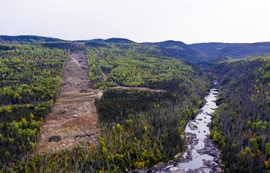 Forêt, petites montagnes, rivière avec un ciel dégagé.