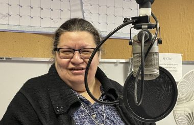 A woman sits at microphone in radio station