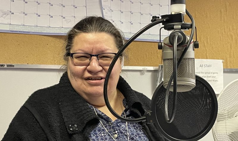 A woman sits at microphone in radio station