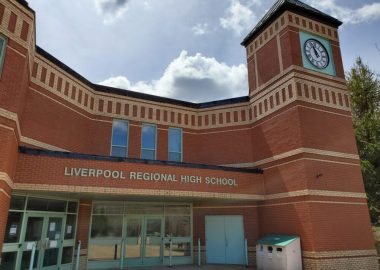 The outside of the brick building of Liverpool Regional High School on a sunny day
