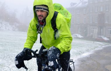 homme sur un vélo sous une tempête de neige