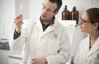 Deux chercheurs de LuminUltra observant un liquide dans un compte-goutte dans un laboratoire