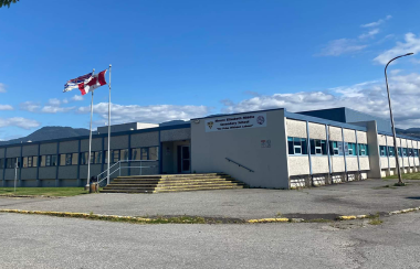 School with a sign that says Mount Elizabeth Secondary School with the B.C. and Canada flags in the front