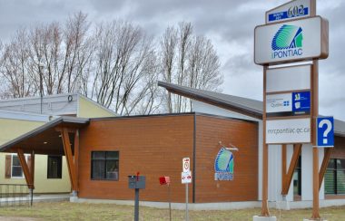 A photo of the exterior of the MRC Pontiac office, featuring brown siding and a large sign with a white background.