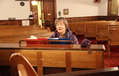 Woman sings and plays piano in an empty church
