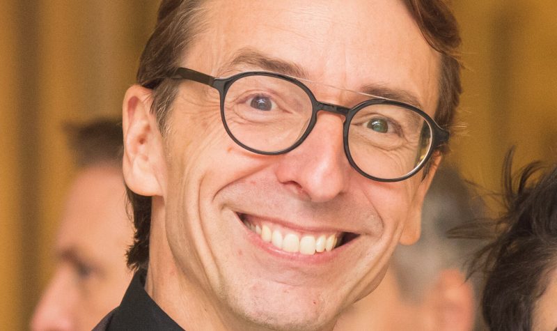 Marco Décelles, directeur général, en avant plan tout sourire et portant des lunettes.