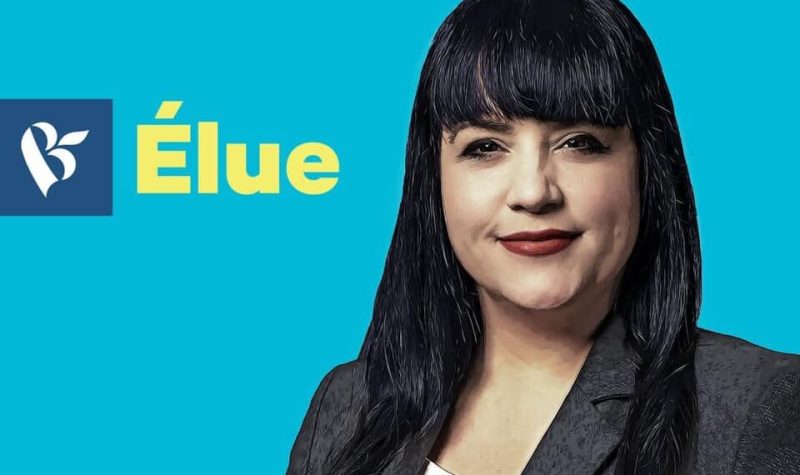 Affiche de la candidate Marilène Gill du Bloc Québécois. Dame aux cheveux noirs, rouge à lèvre rouge foncé, veston gris foncé et chandail blanc sur fond bleu ciel.