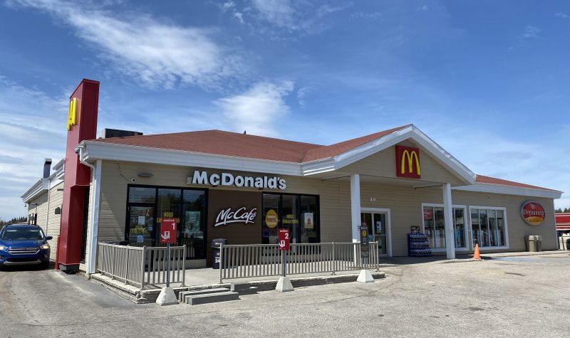 Restaurant McDonald avec stationnement en asphalte et voiture bleue qui est au service au volant.