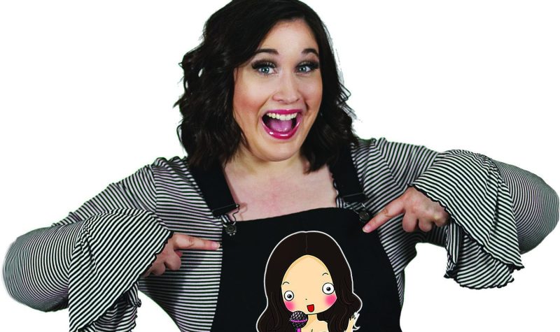 A photo of Molly Wilson smiling and pointing to a cartoon version of herself on her overalls