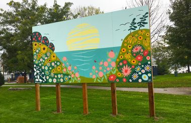 Murale (représentant deux montagnes de fleurs devant la Baie et le soleil) sur cinq pillier sur un gazon vert