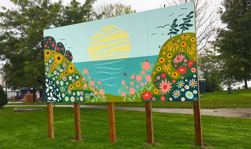 Murale (représentant deux montagnes de fleurs devant la Baie et le soleil) sur cinq pillier sur un gazon vert