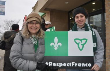 Nadine Lalonde, à gauche, avec une pancarte du drapeau Franco-Ontarien lors d'un rassemblement