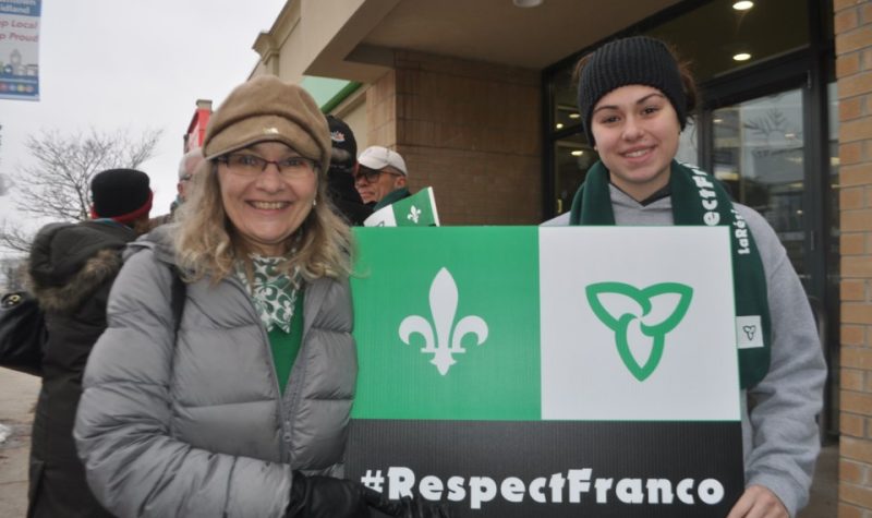Nadine Lalonde, à gauche, avec une pancarte du drapeau Franco-Ontarien lors d'un rassemblement
