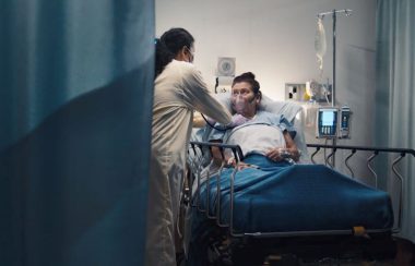 a patient on a hospital bed looks to her nurse for help, but who will help the nurses?