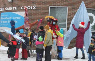 On peut voir des élèves de l'école Sainte-Croix de Lafontaine, à l'extérieur, en compagnie d'animateur de l'activité « Noël au village » . La photo à été prise en face de l'école Saint-Croix et tous semble avoir du plaisir.