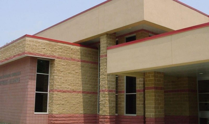 On peut voir une partie du bâtiment de l'École secondaire catholique Nouvelle-Alliance de Barrie. Le bâtiment est en briques beiges et roses.