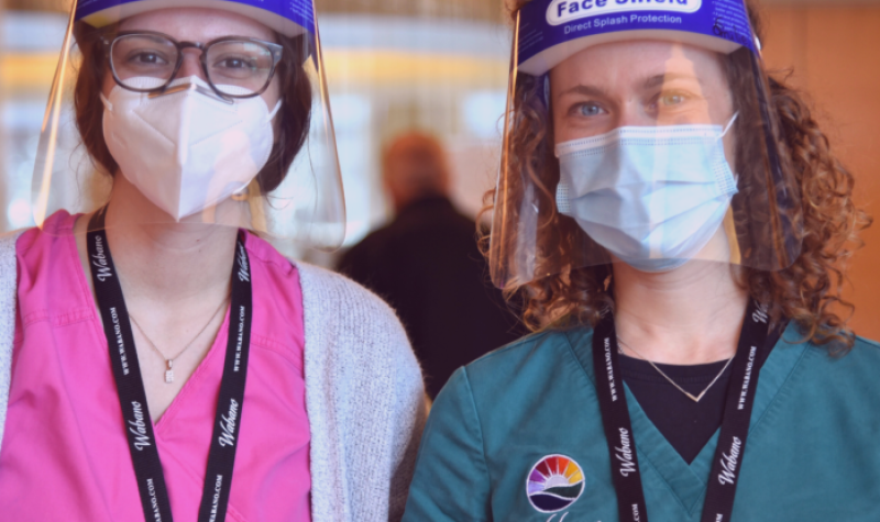 Two nurses stand side-by-side, both wearing face shields, one in an Ottawa Pub;ic Health uniform and the other in a Wabano Centre uniform.