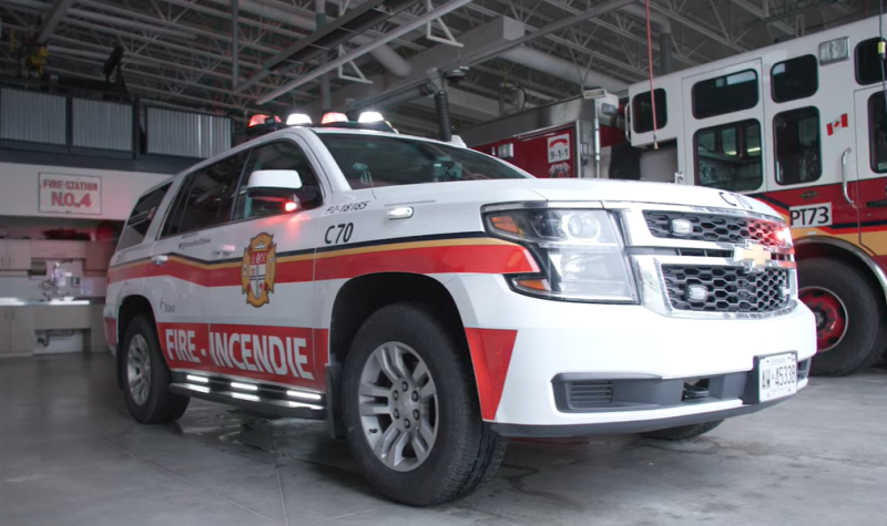 An Ottawa Fire Service vehicle is seen from the front, with a fire truck seen in the background in a spacious garage.