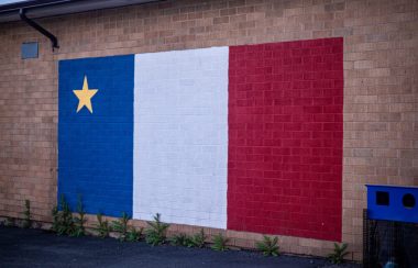 Le drapeau acadien peint sur le mur de l'ancienne école anglophone devenue francophone. Photo : Valentin Alfano