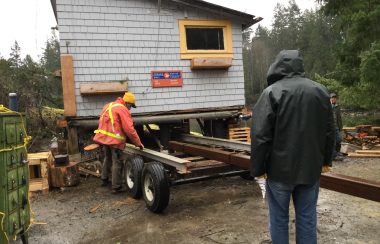 A small building with a Canada Post logo is being loaded onto a trailer.