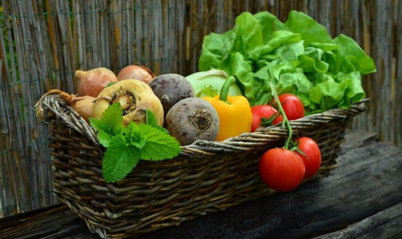 Un panier en osier qui contient des fruits et des légumes