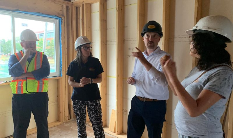 4 people stand together wearing construction helmets inside a room under construction