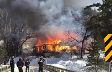 L'édifice du Black River INN en feu avec des pompiers en uniformes ainsi que des policiers