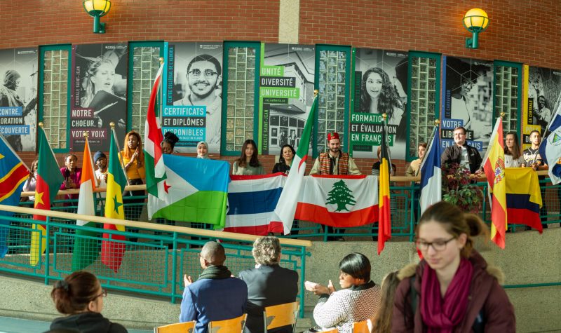 De jeunes étudiants internationaux lèvent des drapeaux représentant le multiculturalisme du Campus Saint-Jean