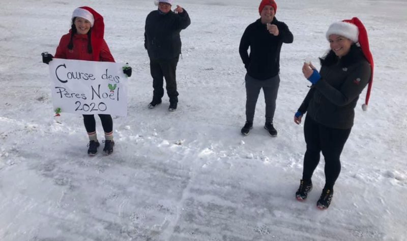 Quatre membres du comité du Club de course de Forestville portant un bonnet de père-noël à l'extérieur et tenant un petit verre. Une affiche indique Course des Père-Noël 2020