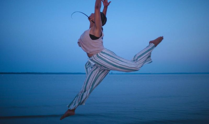 Chloé Saintesprit, danseuse, en mouvements avec les bras vers le haut, au bord de mer