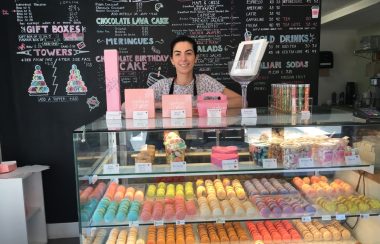 Une femme derrière un comptoir avec des macarons devant elle