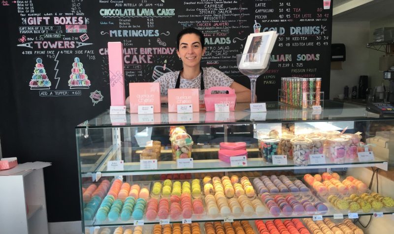 Une femme derrière un comptoir avec des macarons devant elle