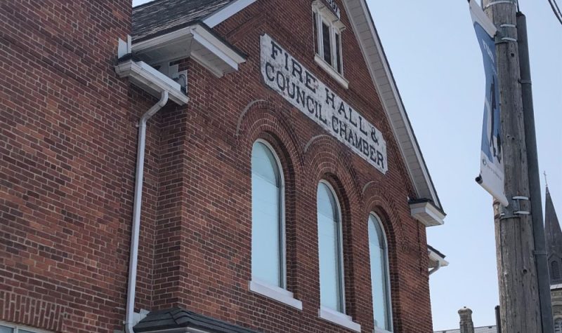 On voit le bâtiment de brique brune de l'ancienne caserne de Penetanguishene. L'inscription « Fire Hall and Council Chamber » apparait sur le bâtiment.