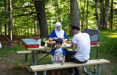 A family cooks at a picnic table in Kejimkujik