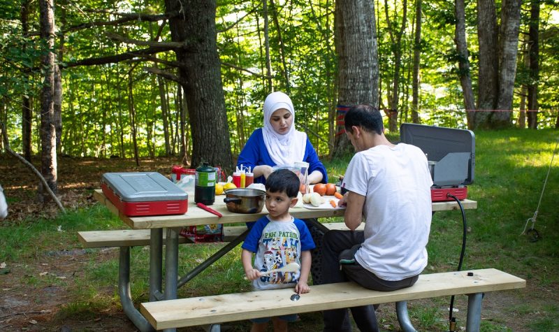 A family cooks at a picnic table in Kejimkujik