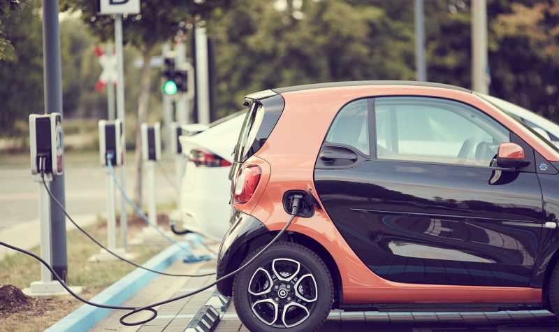 Une petite voiture orange et noire est branchée à un point de recharge.