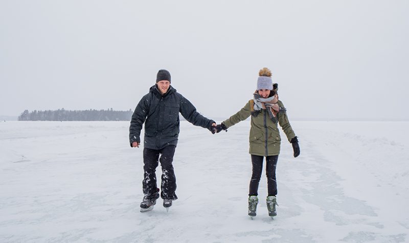Two people skating on a frozen lake in a snow storm