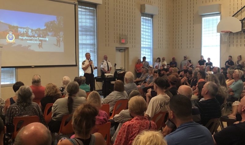 Showing police chief speaking to a packed room