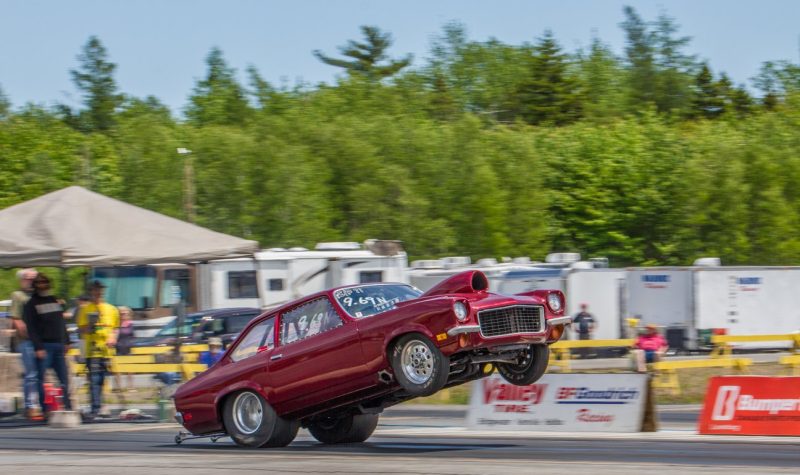 A drag racers lifts the front wheels of a car as it starts a run down the track