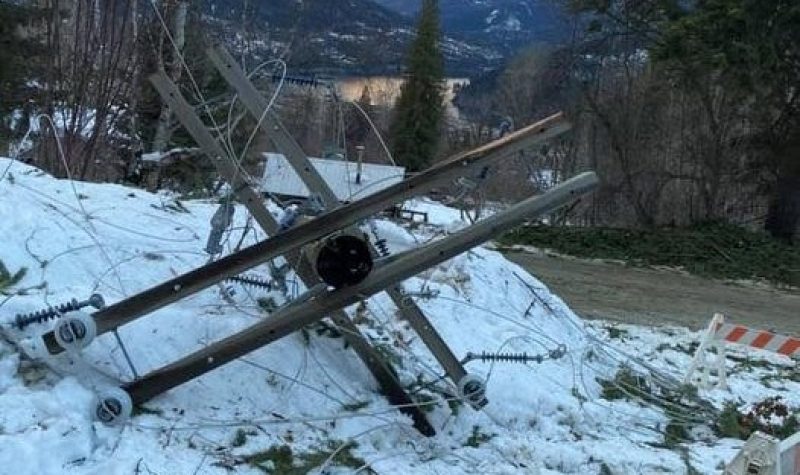 A powerline down on snow with Kootenay Lake in the background.