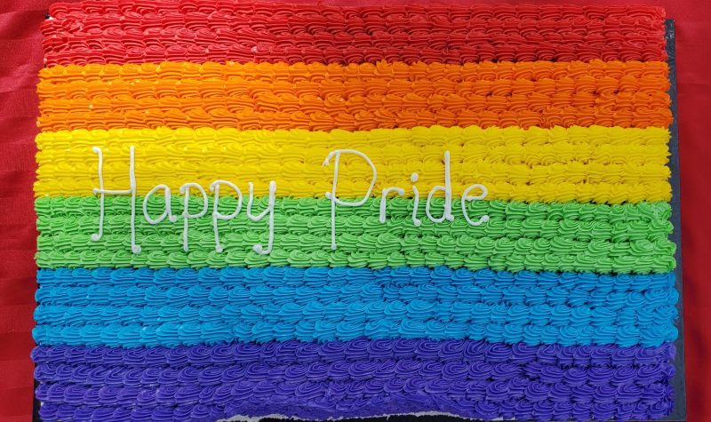 A large cake is decorated in rainbow stripes to celebrate Pride Week.