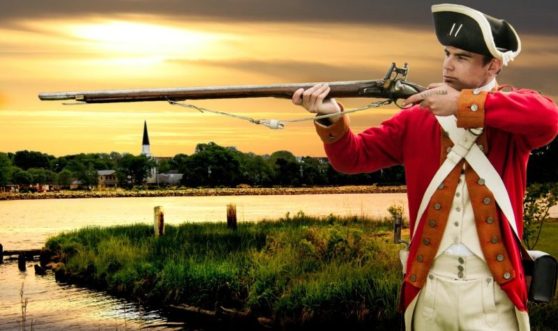 A photo of a privateer with a long gun standing against a backdrop of Nova Scotia at sunset.