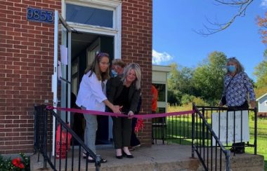 Two women cut a ribbon outside a building