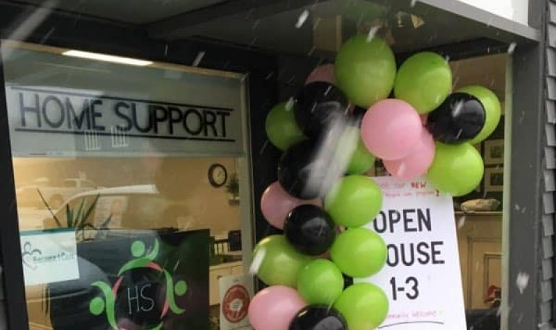 Balloons and signs in a window announce an open house at Queens County Home Support.